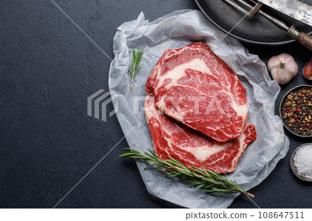 Raw ribeye steaks with savory spices Raw ribeye steaks with savory spices 108647511
