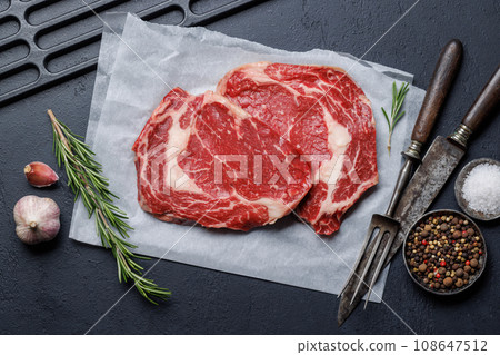 Raw ribeye steaks with savory spices 108647512