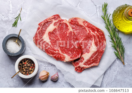 Raw ribeye steaks with savory spices Raw ribeye steaks with savory spices 108647513