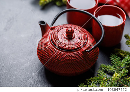 Teapot, cup, and fir tree branches create a cozy scene Teapot, cup, and fir tree branches create a cozy scene 108647552