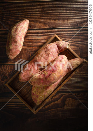 Old sweet potatoes placed on a wooden board. 108647606