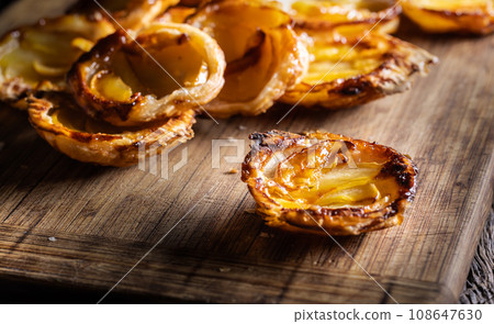 Mini tarts made of puff pastry and sliced apples on a cutting board Mini tarts made of puff pastry and sliced apples on a cutting board 108647630