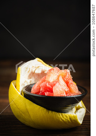 Grapefruits with red flesh placed on a wooden board in a bowl. 108647687