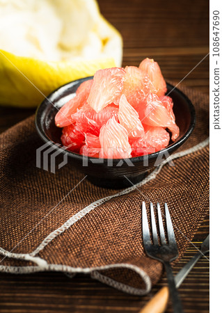 Grapefruits with red flesh placed on a wooden board in a bowl. Grapefruits with red flesh placed on a wooden board in a bowl. 108647690