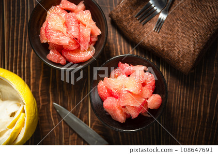 Grapefruits with red flesh placed on a wooden board in a bowl. 108647691