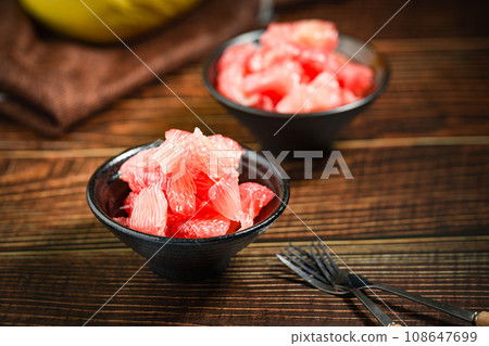 Grapefruits with red flesh placed on a wooden board in a bowl. 108647699