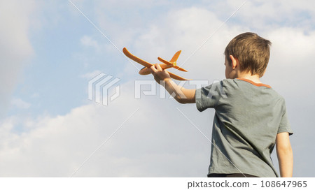 Little boy launches a toy plane into the air. Child launches a toy plane 108647965