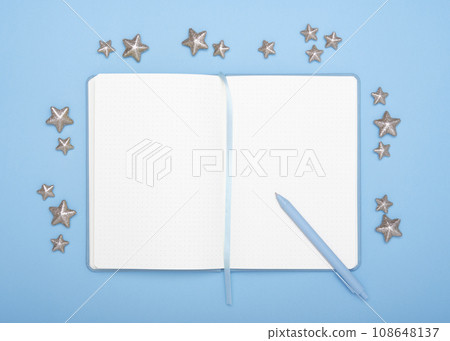 Open diary for plans for the new year with pen decorated with stars on cyan background. Concept of planning new year. Open diary for plans for the new year with pen decorated with stars on cyan background. Concept of planning new year. 108648137