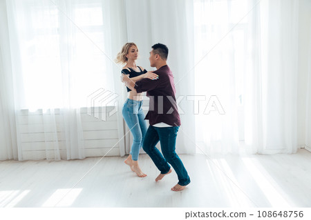 Dancing man and woman in the dance hall of the studio show a dance Dancing man and woman in the dance hall of the studio show a dance 108648756