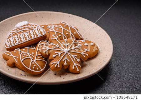 Beautiful Christmas gingerbread cookies of different colors on a ceramic plate Beautiful Christmas gingerbread cookies of different colors on a ceramic plate 108649171