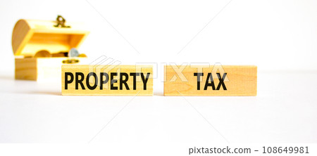 Property tax symbol. Concept words Property tax on wooden blocks. Beautiful white table white background. Wooden chest with coins. Business and property tax concept. Copy space. 108649981
