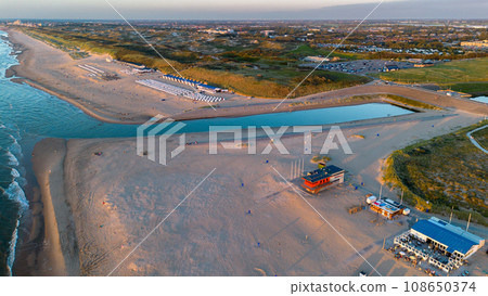 Netherlands. Beautiful flight in summer over the beach in Katwijk aan Zee. People are resting near the sea. Houses for tourists. Beach umbrellas, rides 108650374