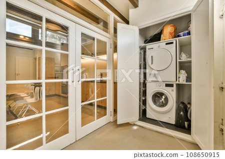 a laundry room with a washer, dryer and washing machine in the corner between the door to the kitchen 108650915