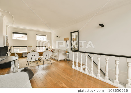 a living room with white walls and hardwood flooring, including a staircase leading up to the upper landing area a living room with white walls and hardwood flooring, including a staircase leading up to the upper landing area 108650916