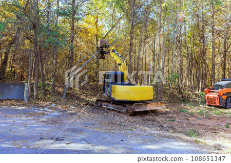 Using tractor builder uproots trees in forest preparation for construction on land Using tractor builder uproots trees in forest preparation for construction on land 108651347