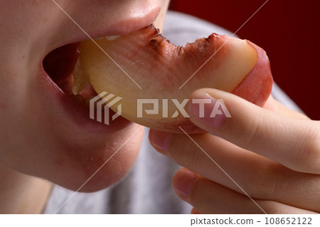 female hand putting a piece of ripe peach in the mouth, healthy food dessert female hand putting a piece of ripe peach in the mouth, healthy food dessert 108652122