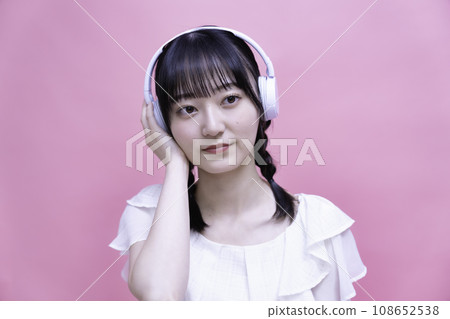 在智能手機上聽音樂的年輕女子帶耳機 在智能手機上聽音樂的年輕女子帶耳機 108652538