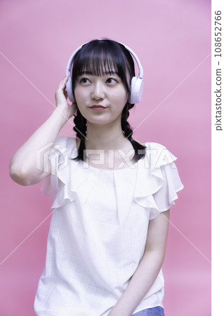 Young woman listening to music on smartphone with headphones Young woman listening to music on smartphone with headphones 108652766