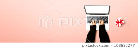 Person using a laptop computer with a gift box Person using a laptop computer with a gift box 108653277