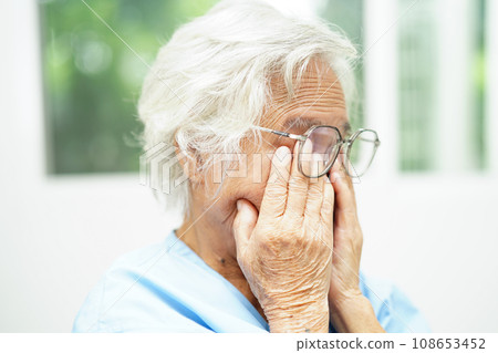 Asian senior woman wearing eyeglasses reduce headache and eyestrain suffer at home care service. Asian senior woman wearing eyeglasses reduce headache and eyestrain suffer at home care service. 108653452