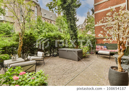 an outdoor living area with furniture and trees in the fore - image is taken from google's street view 108654187