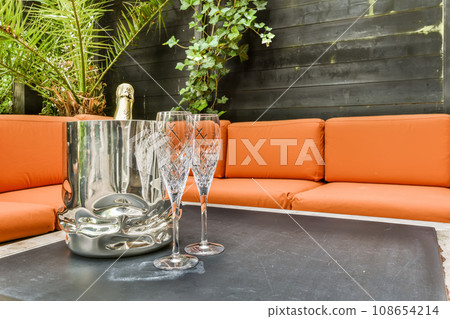 two wine glasses on a table with an orange couch in the photo is taken to the right, and it's not clear two wine glasses on a table with an orange couch in the photo is taken to the right, and it's not clear 108654214