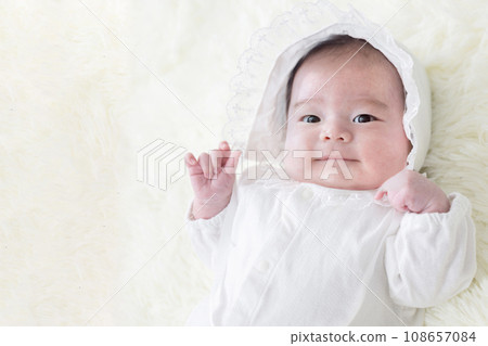 Baby in a cute baby dress raising his hand Baby in a cute baby dress raising his hand 108657084