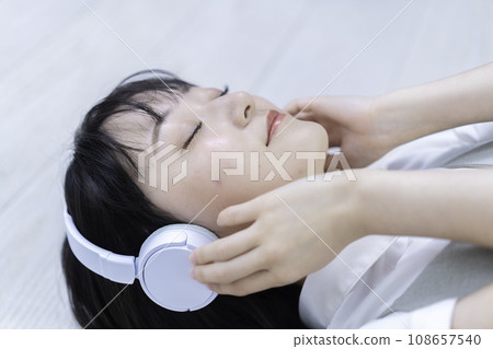 A young woman lying on the floor and soaking in music 108657540