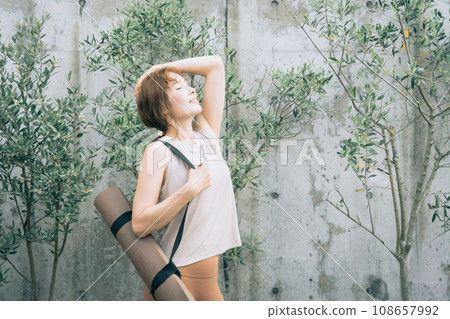 A woman doing garden yoga in the garden and holding a yoga mat (workout, exercise, health, diet) A woman doing garden yoga in the garden and holding a yoga mat (workout, exercise, health, diet) 108657992