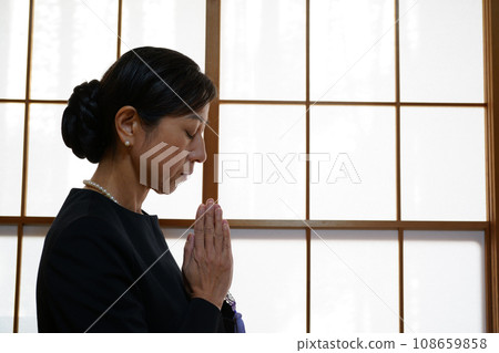 身穿喪服的中年婦女雙手合十 108659858