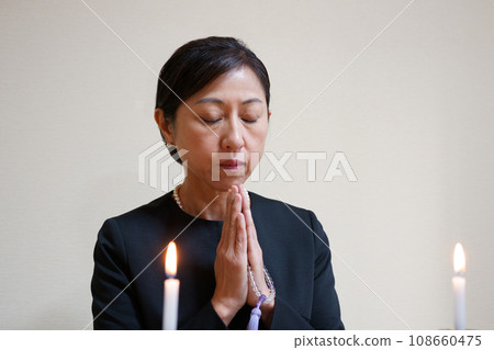 身穿喪服的中年婦女雙手合十 身穿喪服的中年婦女雙手合十 108660475