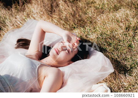 Beauty image of a woman lying on a meadow in the evening Beauty image of a woman lying on a meadow in the evening 108660921