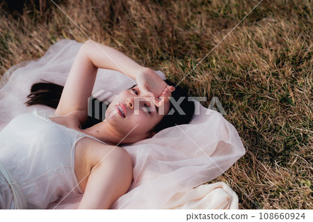 Beauty image of a woman lying on a meadow in the evening 108660924
