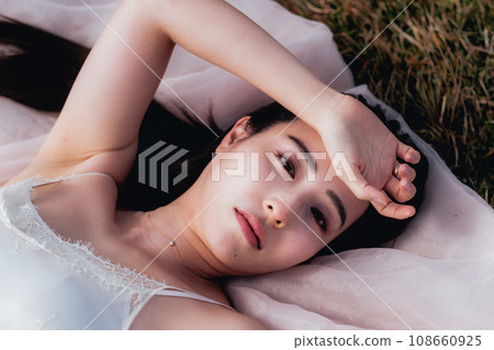 Beauty image of a woman lying on a meadow in the evening 108660925