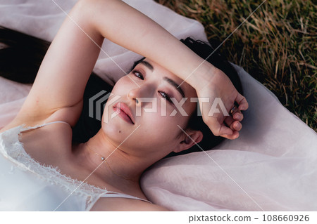 Beauty image of a woman lying on a meadow in the evening 108660926