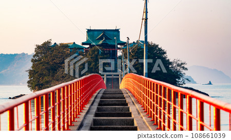 A shrine visible beyond the red pier illuminated by the sunset A shrine visible beyond the red pier illuminated by the sunset 108661039