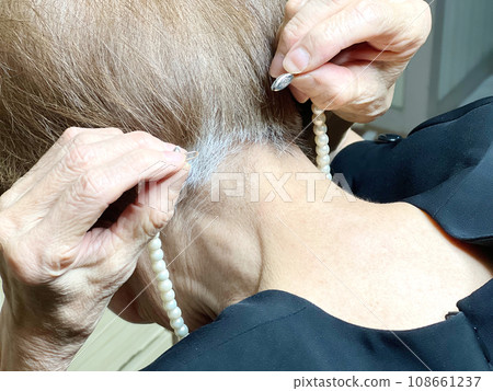 穿著喪服的老婦試著戴上珍珠項鍊 穿著喪服的老婦試著戴上珍珠項鍊 108661237