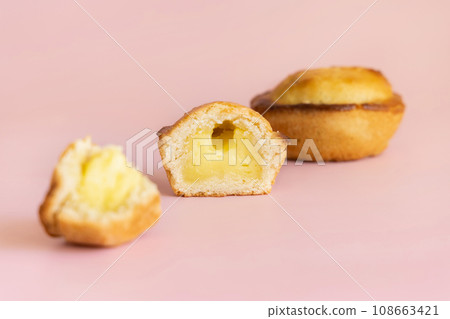 Pasticciotto leccese pastry filled with egg custard cream on a light pink, close up Pasticciotto leccese pastry filled with egg custard cream on a light pink, close up 108663421