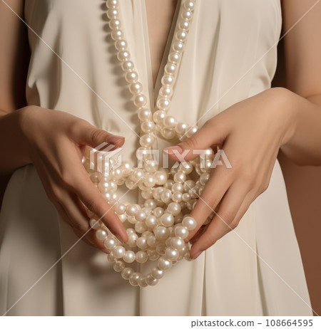 hands holding white pearl necklaces 108664595