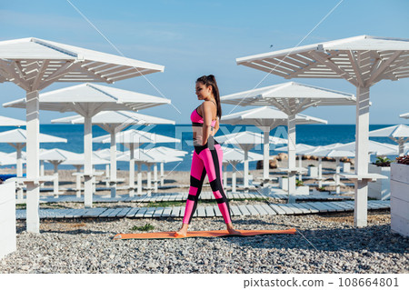 Woman in tracksuit on the beach doing exercises workout warm-up sports Woman in tracksuit on the beach doing exercises workout warm-up sports 108664801