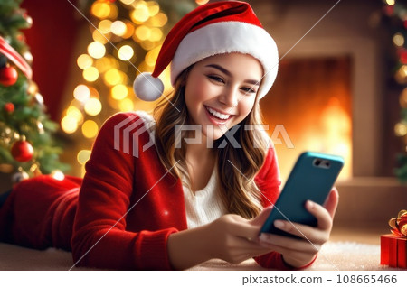 Cheerful smiling Xmas girl in Santa cap excited with good news about gift, looking at smartphone screen, reading text, chatting online, celebrating Christmas holiday, enjoying New Year 108665466