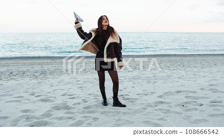 Happy girl dancing on the beach near the ocean in winter overcast day 108666542
