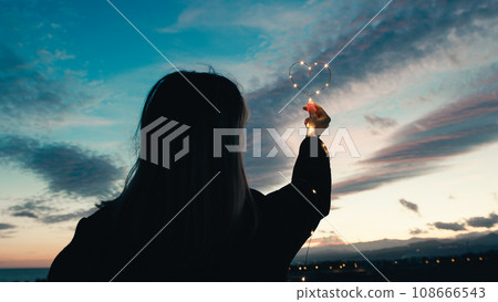 silhouette of Girl with Heart symbol in the sky 108666543