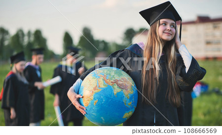 A graduate student poses with a globe in front of her friends. 108666569