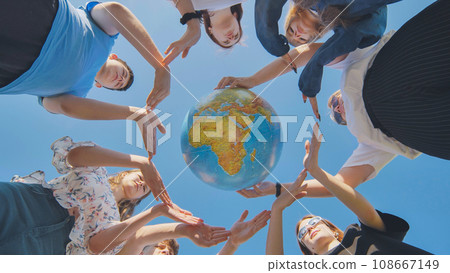 Young boys surround the globe of the world with their palms. 108667149