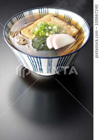 Hot fox soba with fried tofu, kamaboko, wakame, and green onion photographed against a black background Hot fox soba with fried tofu, kamaboko, wakame, and green onion photographed against a black background 108667240