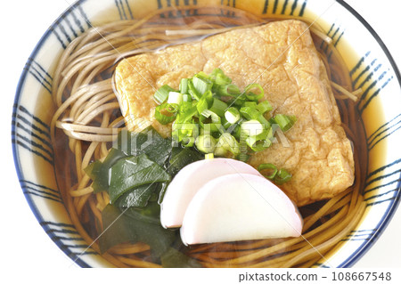 白色背景下,頭頂上放著熱騰騰的蕎麥麵,上面放著炸豆腐、魚板、裙帶菜和蔥 白色背景下,頭頂上放著熱騰騰的蕎麥麵,上面放著炸豆腐、魚板、裙帶菜和蔥 108667548