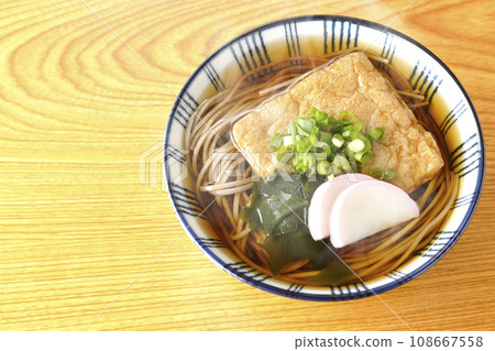 An overhead shot of piping hot fox soba topped with fried tofu, kamaboko, wakame, and green onions. An overhead shot of piping hot fox soba topped with fried tofu, kamaboko, wakame, and green onions. 108667558