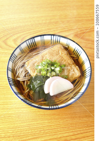 頭頂上放著熱騰騰的狐狸蕎麥麵,上面放著炸豆腐、魚糕、裙帶菜和大蔥。 頭頂上放著熱騰騰的狐狸蕎麥麵,上面放著炸豆腐、魚糕、裙帶菜和大蔥。 108667559