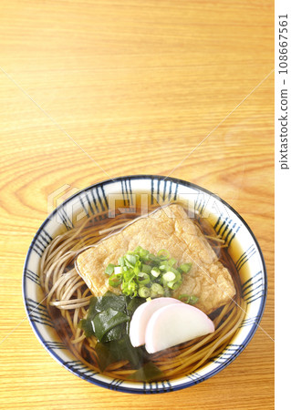 An overhead shot of piping hot fox soba topped with fried tofu, kamaboko, wakame, and green onions. An overhead shot of piping hot fox soba topped with fried tofu, kamaboko, wakame, and green onions. 108667561